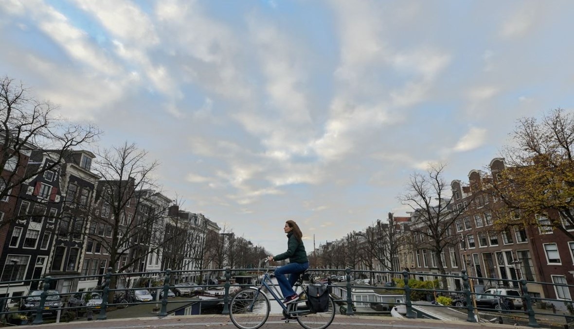 صورة تعبيرية- امرأة تركب دراجة في أمستردام غرب هولندا (24 ت2 2021، أ ف ب). 