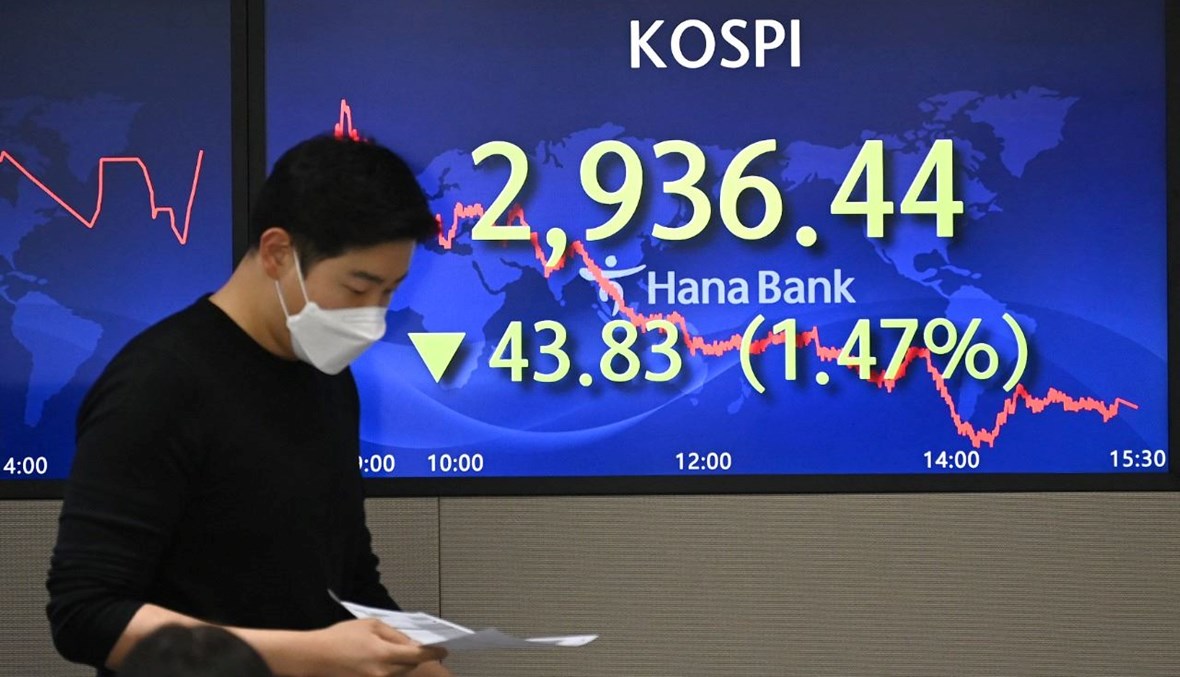 تاجر عملات يمر قرب شاشة تعرض مؤشر الأسهم القياسي لكوريا الجنوبية في غرفة التداول في "كاي اي بي هانا بنك" في سيول (26 ت2 2021، أ ف ب). 