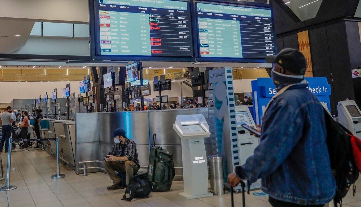 مسافر يننظر إلى لوحة إعلانات إلكترونية تعرض الرحلات الملغاة في مطار أو آر تامبو الدولي في جوهانسبرغ (أ ف ب).