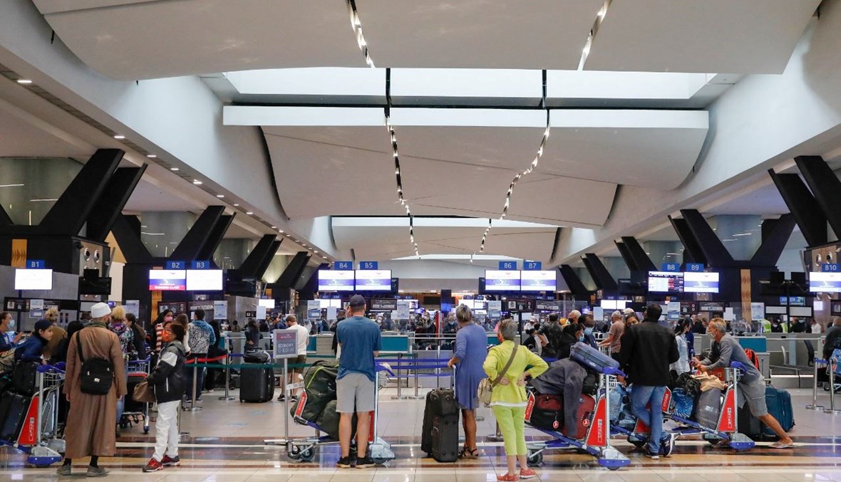 مسافرون يقفون بالصف عند مكتب تسجيل الوصول في مطار أو آر تامبو الدولي في جوهانسبرغ (27 ت2 2021، أ ف ب). 