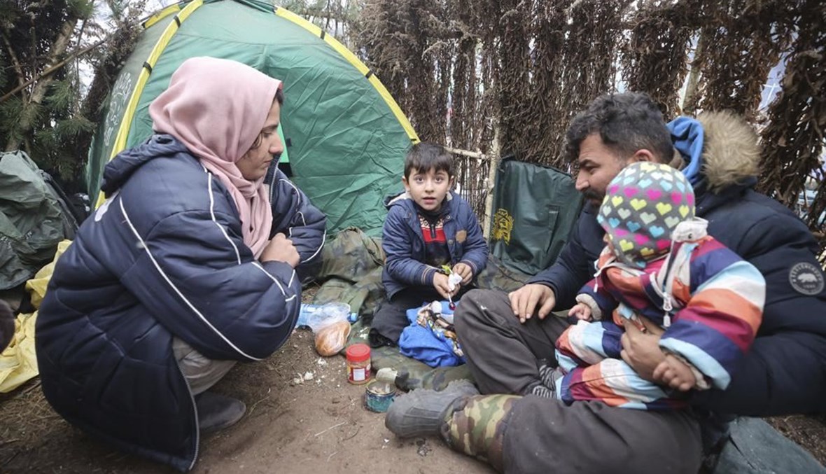 عائلة في مخيم تجمع فيه المهاجرون على الحدود بين بيلاروسيا  وبولندا بالقرب من غرودنو في بيلاروسيا (13 ت2 2021، أ ب). 