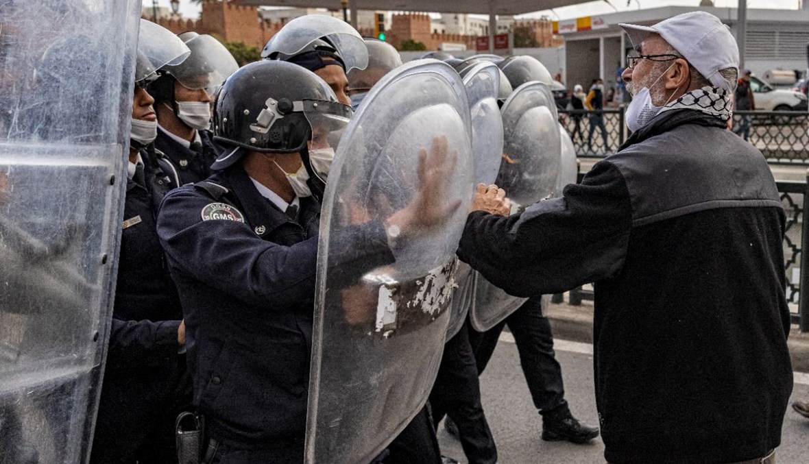 عناصر من شرطة مكافحة الشغب المغربية يمنعون متظاهرين يحتجون في  الرباط على تطبيع العلاقات مع إسرائيل (24 ت2 2021، أ ف ب). 