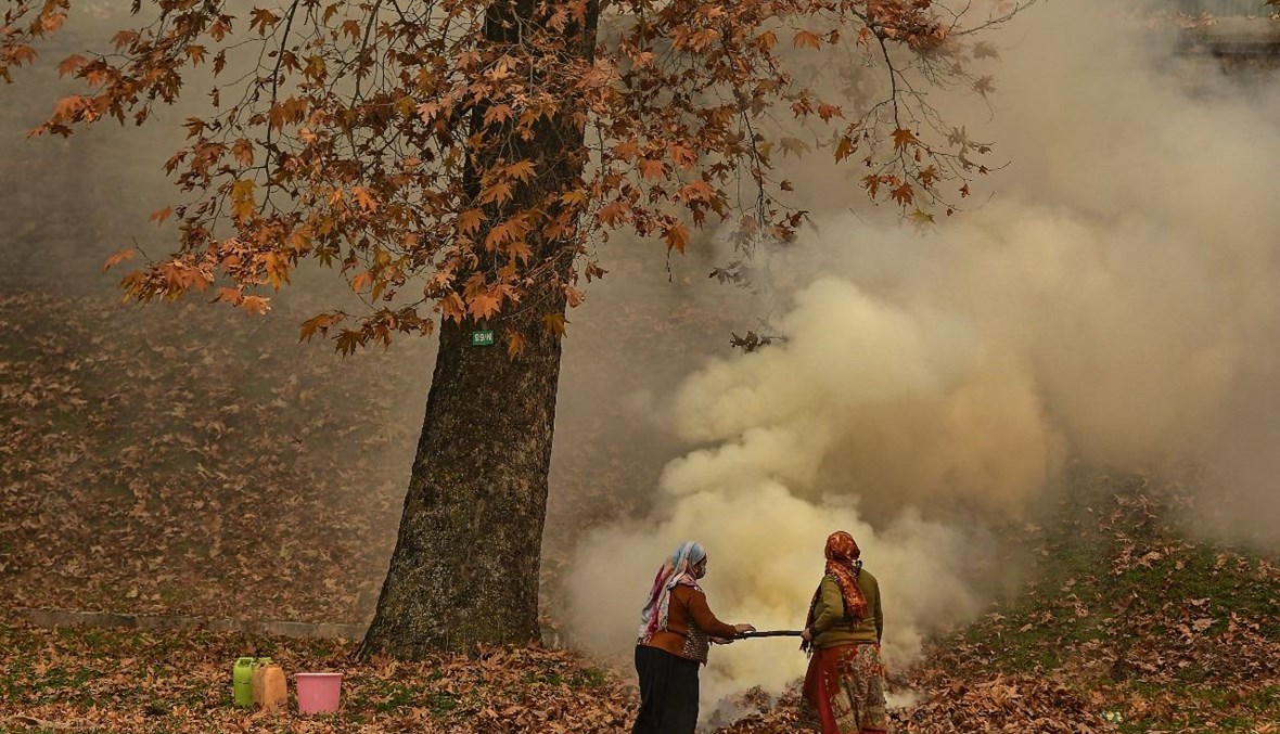 امرأتان تحرقان أوراق القيقب في حديقة نيشات باغ في سريناغار بالهند (29 ت2 2021، أ ف ب). 