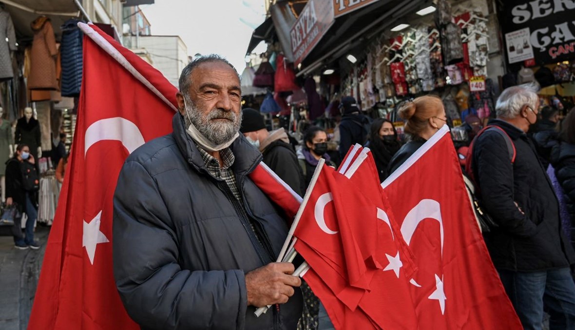 بائع للأعلام التركية يقف في منطقة محمود باشا بالقرب من البازار الكبير في اسطنبول (2 ك1 2021، أ ف ب).