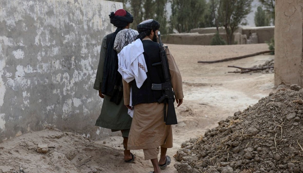 عنصران من طالبان يمشيان في قرية سبروان في منطقة بانجواي في قندهار، قرب مسقط رأس هبة الله أخوند زاده (7 ت2 2021، أ ف ب). 