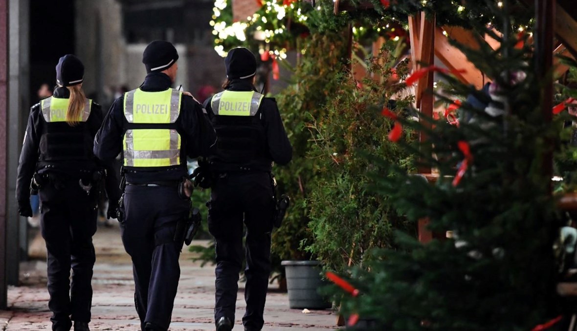 عناصر من الشرطة يمرون قرب أكشاك في سوق الميلاد في مدينة إيسن غرب ألمانيا (29 ت2 2021، أ ف ب). 