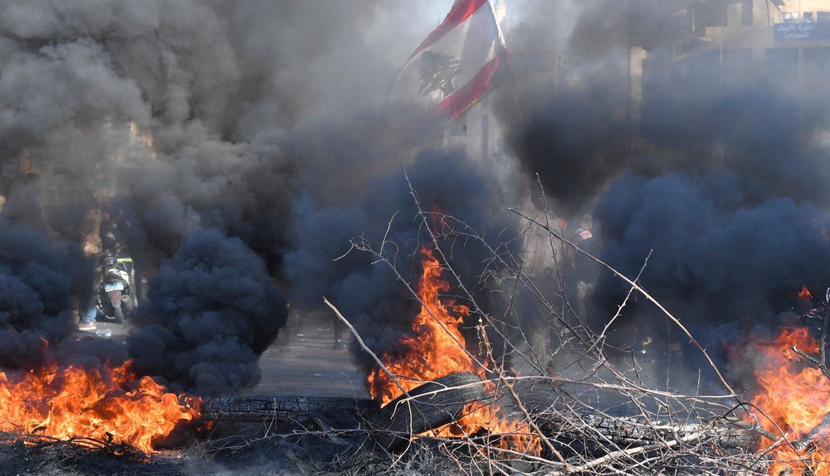 العلم اللبنانيّ وسط دخان الإطارات المشتعلة (حسن عسل).