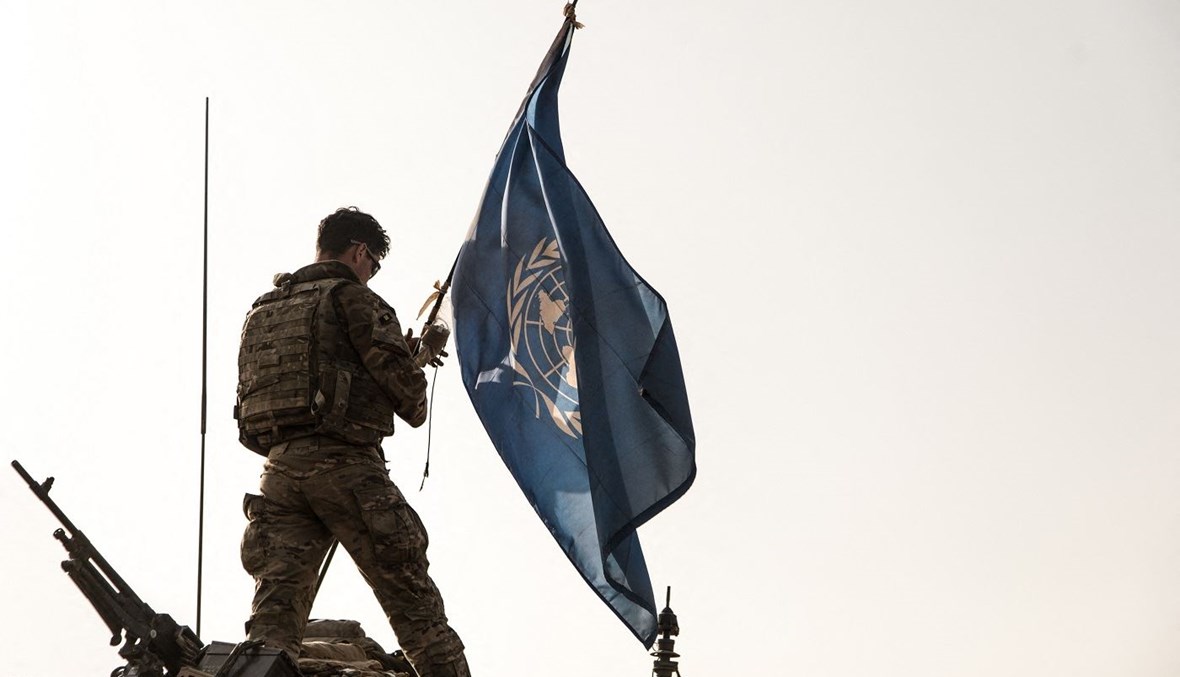 جنديّ بريطانيّ من بعثة الأمم المتحدة في مالي يرفع علم المنظمة الأممية على سطح مركبة مدرّعة خفيفة خلال دورية في ميناكا (أ ف ب).