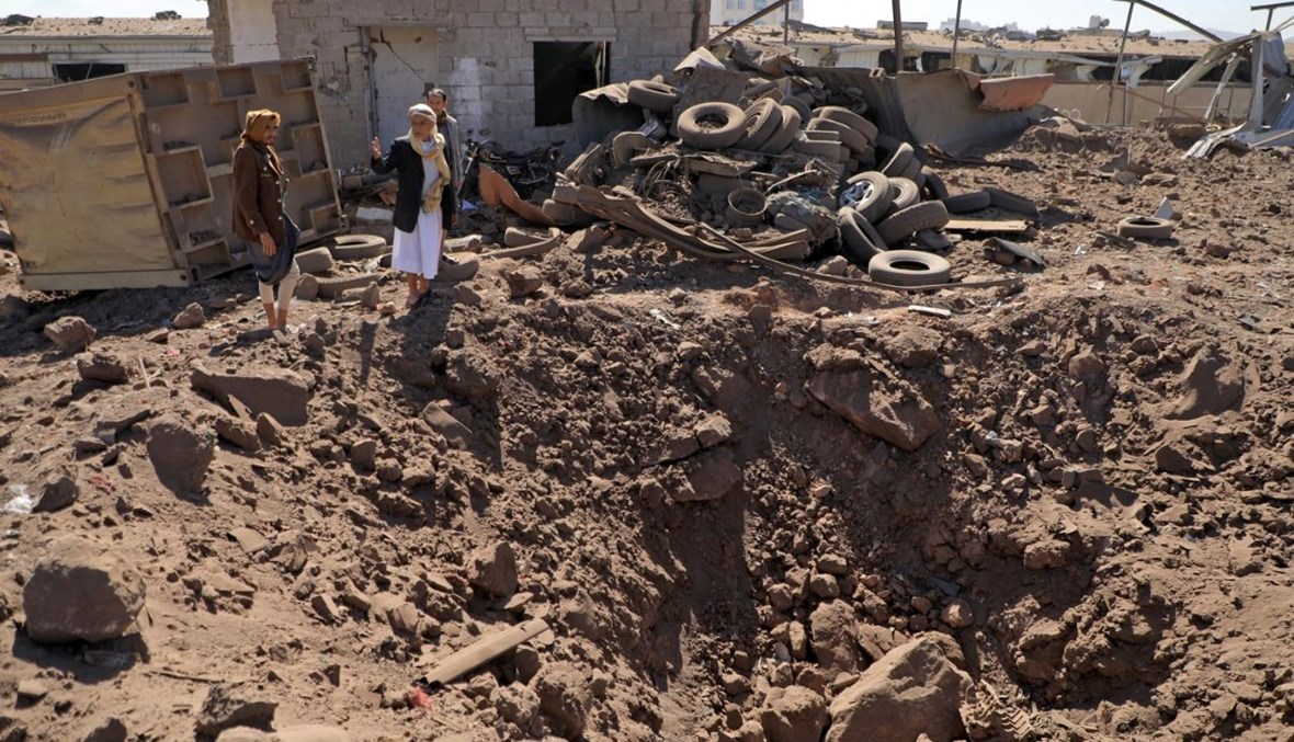 يمنيون يتفقدون موقع ضربات جوية استهدفت ورشة لتصليح السيارات في صنعاء (5 ك1 2021، أ ف ب).