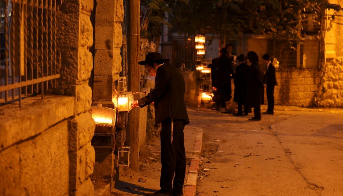 يهود متشددون يضيئون الشموع في القدس، في الليلة الثامنة والأخيرة من عيد هانوكا اليهودي (5 ك1 2021، أ ف ب). 