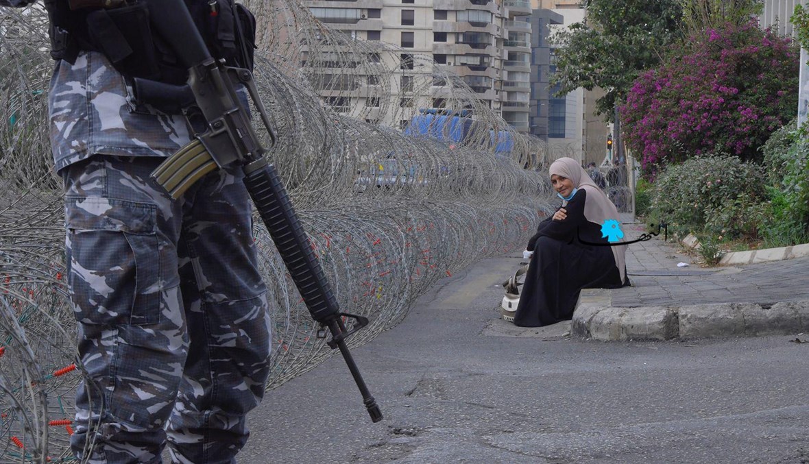 سيدة تجلس على الرصيف وسط إجراءات أمنية مشددة في محيط الأونيسكو (نبيل اسماعيل).