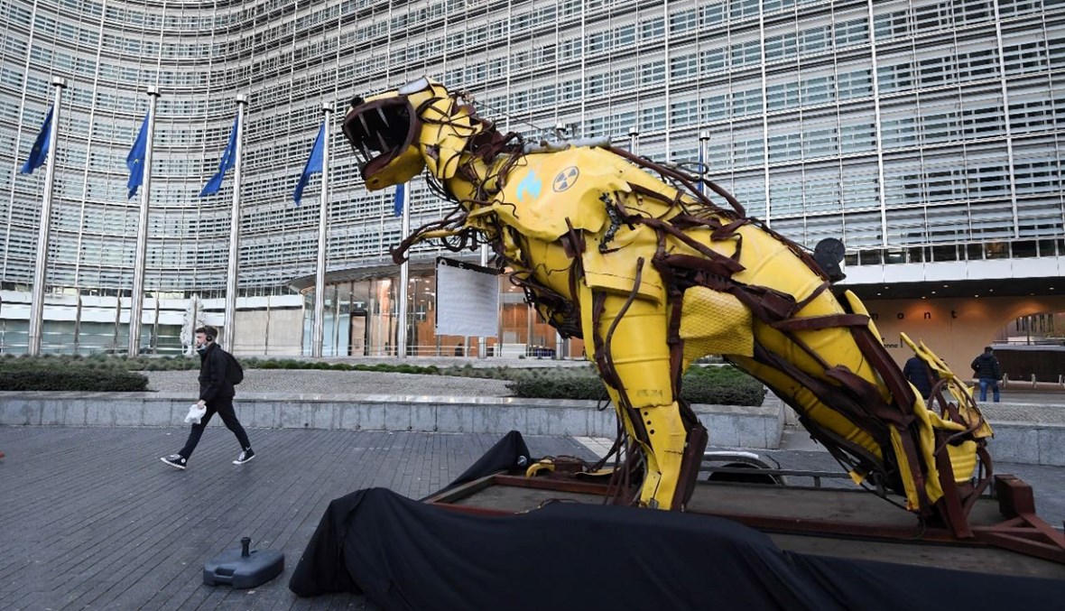 تمثال نصبه نشطاء "غرينبيس" يمثّل ديناصورًا عملاقًا برموز مشعة ولهب غاز أزرق، خارج مقر المفوضية الأوروبية في بروكسيل، احتجاجًا على إدراج الغاز الأحفوري والطاقة النووية في قائمة الاتحاد الأوروبي للاستثمارات المستدامة في بروكسيل (7 ك1 2021، ا ف ب). 