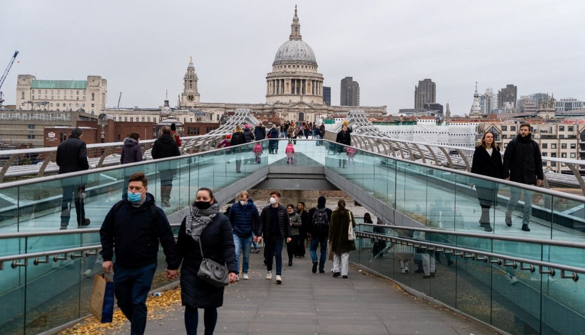 اشخاص يعبرون جسر الألفية عند نهر التايمز في وسط لندن. وبدت كاتدرائية القديس بولس في الخلفية (11 ك1 2021، ا ف ب). 
