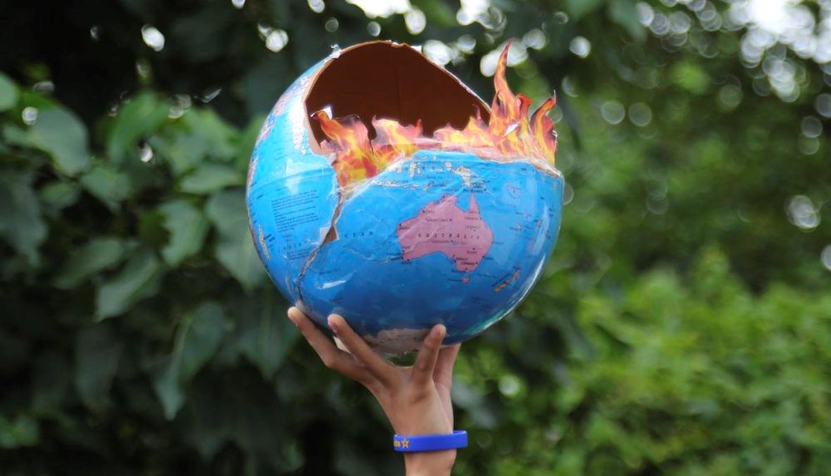 فتاة تمسك مجسماً لكوكب الأرض وهو يحترق اعتراضاً على التلكؤ في مواجهة التغير المناخي- 2019 - "أ ف ب" 