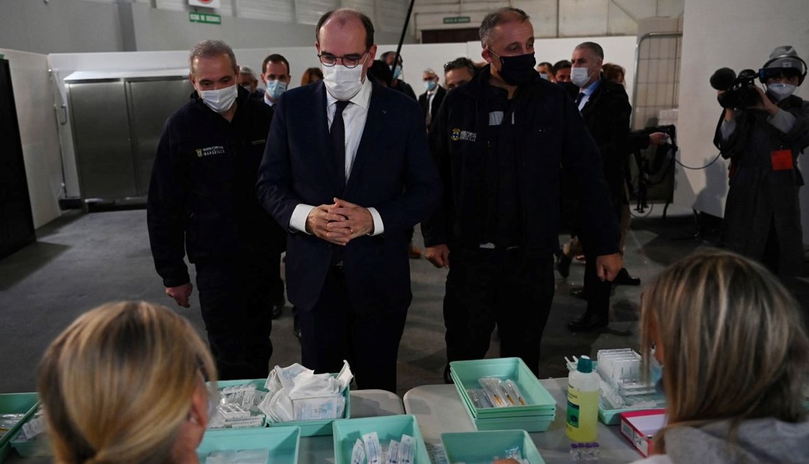 رئيس الوزراء الفرنسي جان كاستكس (في الوسط) يتفقد ممرضات خلال عملهن في مركز تطعيم في بارك شانو في مرسيليا جنوب فرنسا (13 ك1 2021، أ ف ب). 