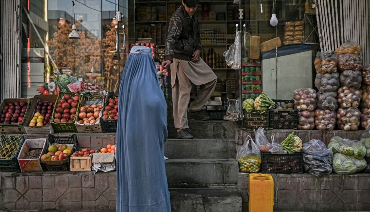 امرأة بالبرقع تشتري بقالة من متجر في كابول (16 ك1 2021، ا ف ب). 