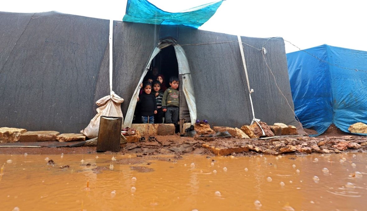 صورة تعبيرية- أطفال في مخيم للسوريين النازحين غمرته الأمطار الغزيرة بالقرب من قرية كفر عروق في محافظة إدلب شمال سوريا (8 ك1 2021، أ ف ب). 