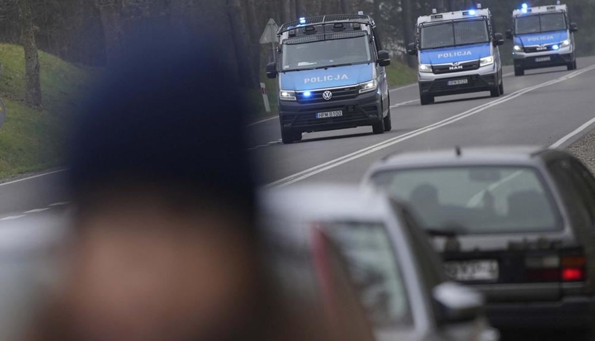 سيارات للشرطة البولندية تمر عبر نقطة تفتيش بالقرب من كوزنيكا عند الحدود مع بيلاروسيا (16 ت2 2021، أ ب). 