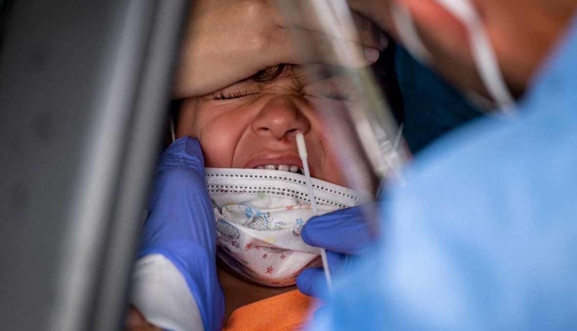 عامل صحي يأخذ مسحة انفية من طفل في مركز اختبار في سان خوان في بورتوريكو (18 ك1 2021، أ ف ب). 