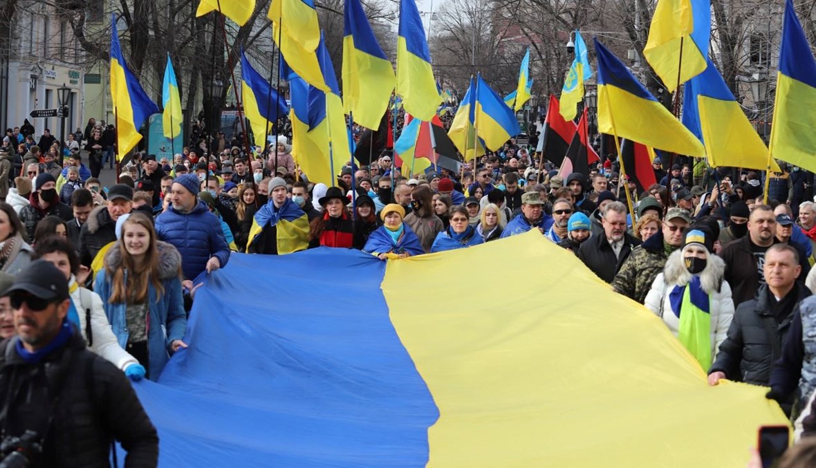 متظاهرون يحملون علمًا أوكرانيًا كبيرًا في مدينة أوديسا جنوب أوكرانيا خلال مسيرة لإظهار الوحدة (20 شباط 2022، أ ف ب). 