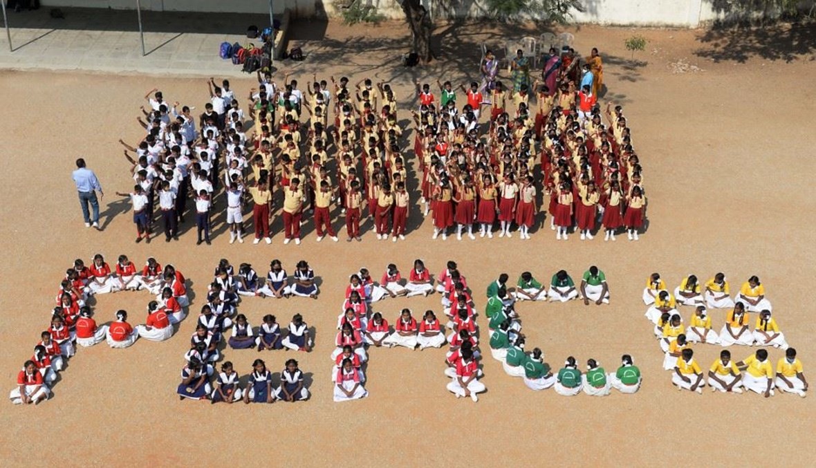 طلاب من مدرسة سانت جوزيف الثانوية يجلسون في ساحة المدرسة لتشكيل كلمة "سلام" (أ ف ب).